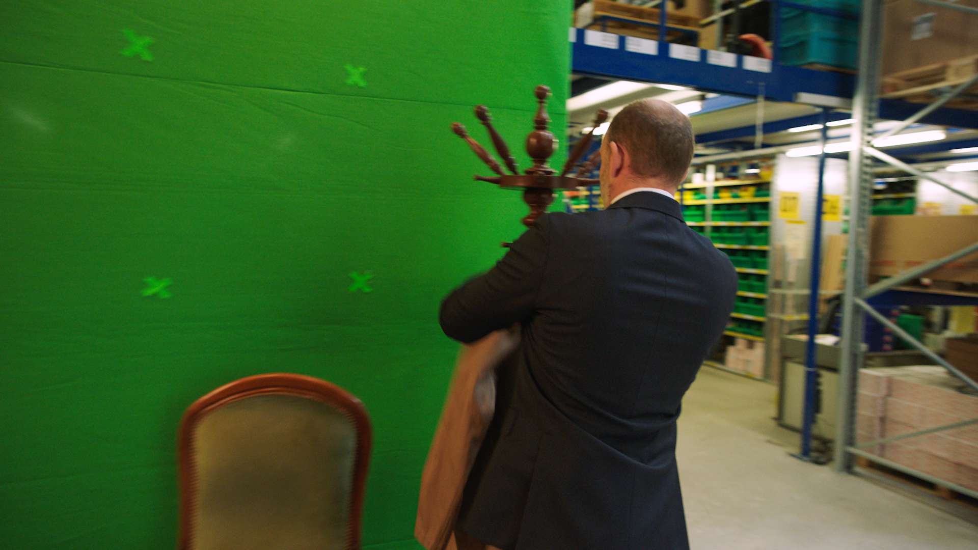 The main actor of the bank avera commercial hanging a coat infront of a empty greenscreen.