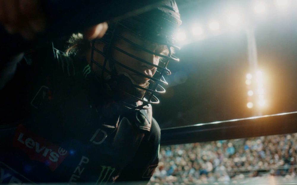 The bullrider Derek Kolbaba perparing for a ride in front of a crowd in a stadium at night.