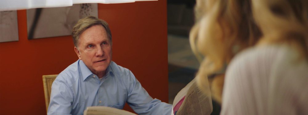 The father of elenore in the short film elenore talking to his wive while holding his newspaper.