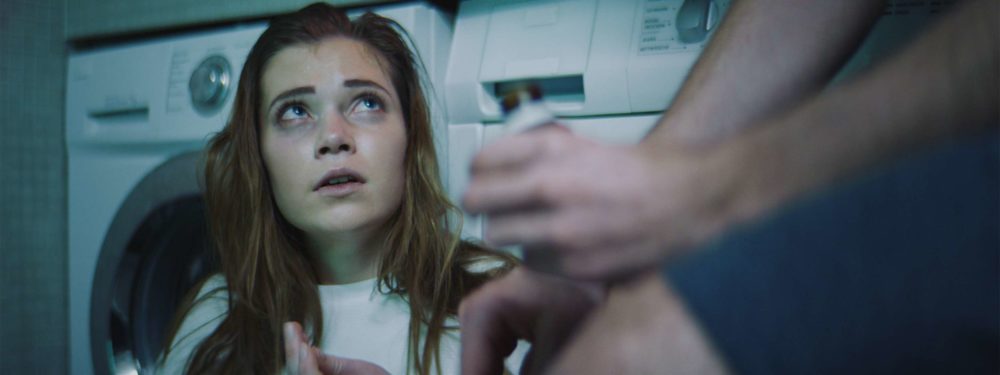 Fariana Flebbe, the main actress of Elenore sitting in front of washing machines in green light.