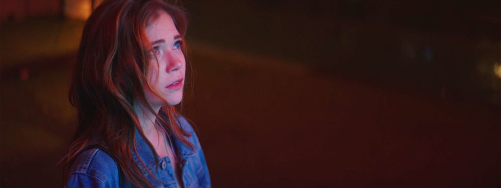 Farina Flebbe, the main actress of the shortfilm elenore looking at a neon advert at night.