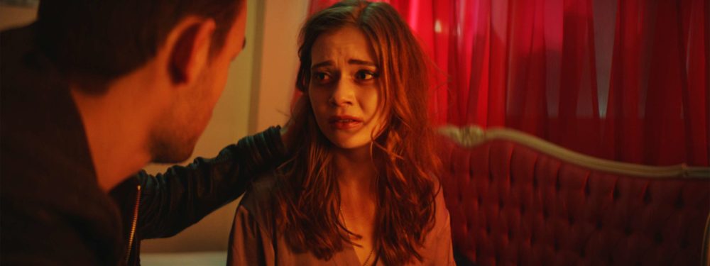 The two main characters of the shortfilm elenore sitting on a bed in red light in a bordell.