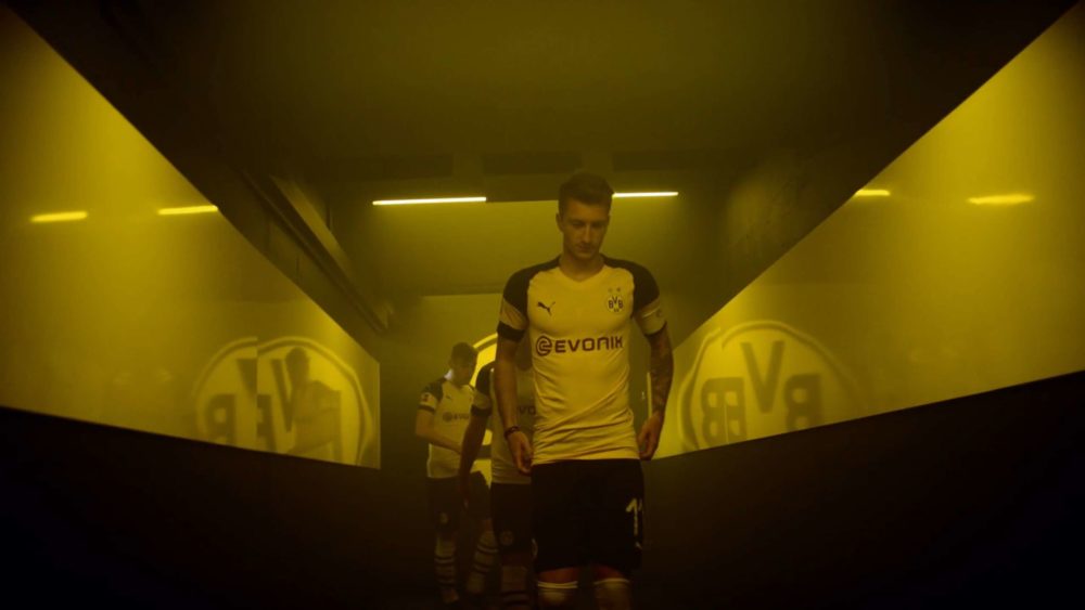 A player of the Borussia Dortmund football club walking into the stadium at night and with fog.
