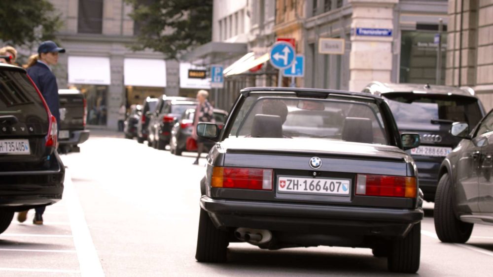 A person in a car driving through the city of zurich while being filmed for the commercial twint.