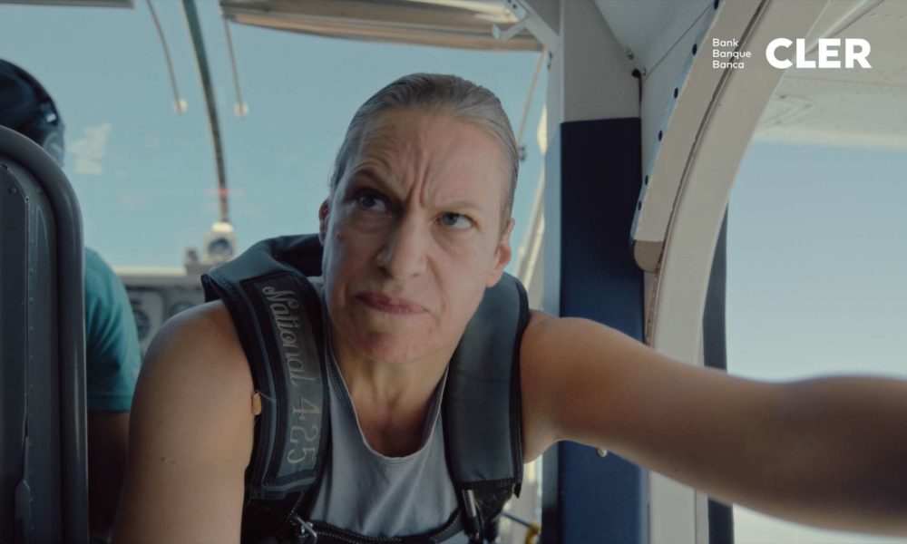 An angry looking woman is opening the door of an airplane on a sunny day.