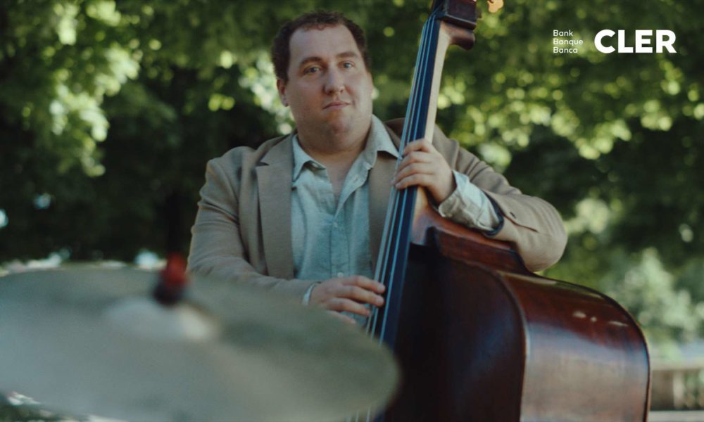 A musician playing the double bass beneath some trees on a sunny day.