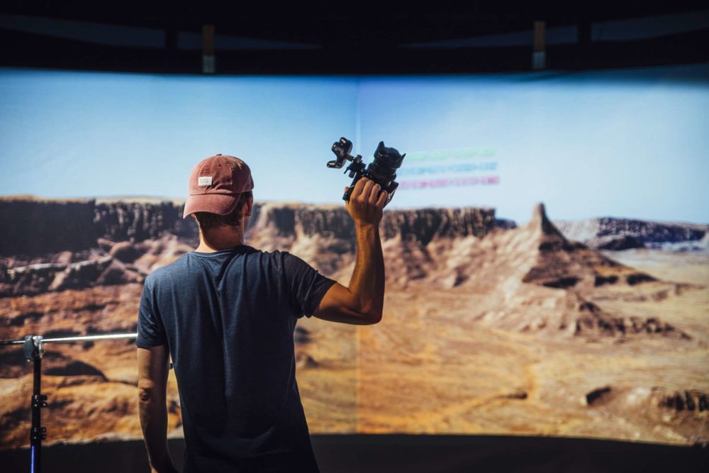 Adrian Weber holding a camera in front of a virtual production setup.