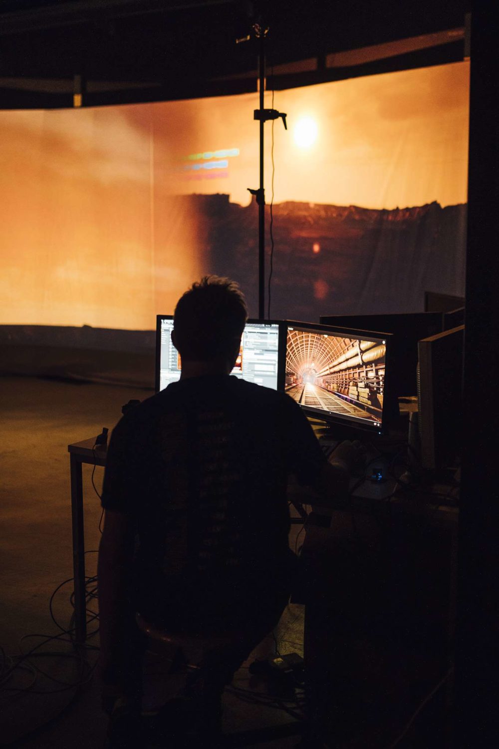 A person looking at two pc monitors in front of a virtual production setup.