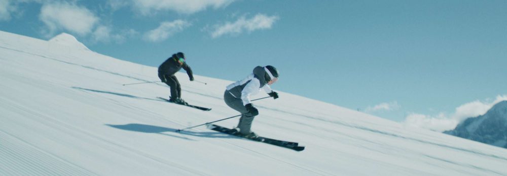 Two skiers going down a perfect slope on a wonderful winter day.