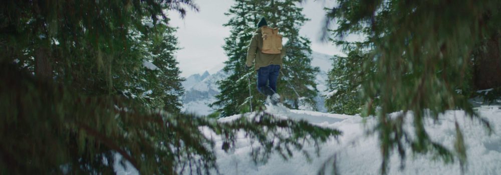 A man with snow-boots walking through a winter landscape.