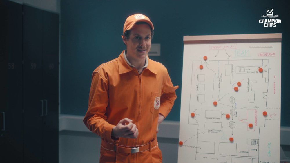 A person in an orange suit standing in front of a writing board