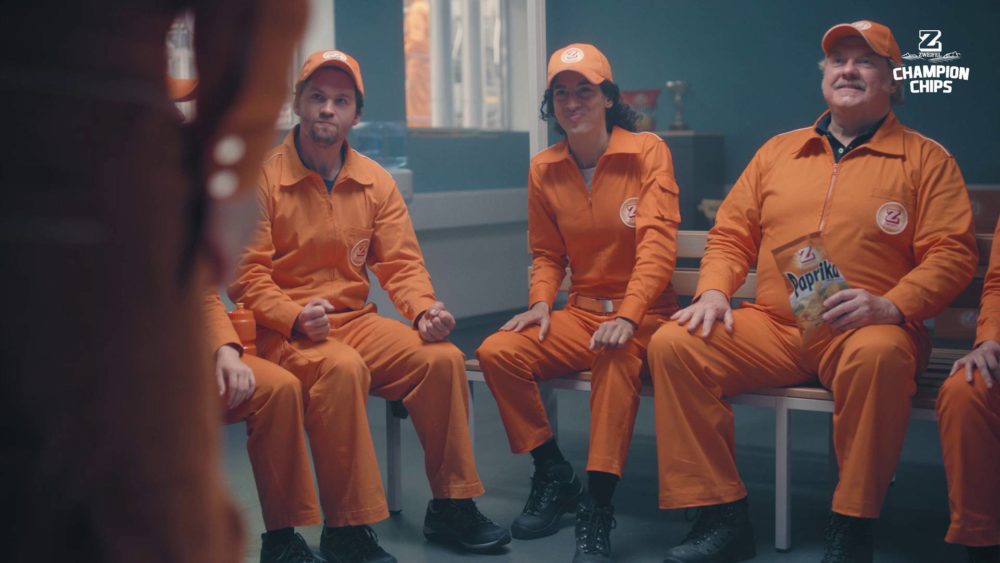 A group of persons in orange suits sitting in a break room in a meeting.