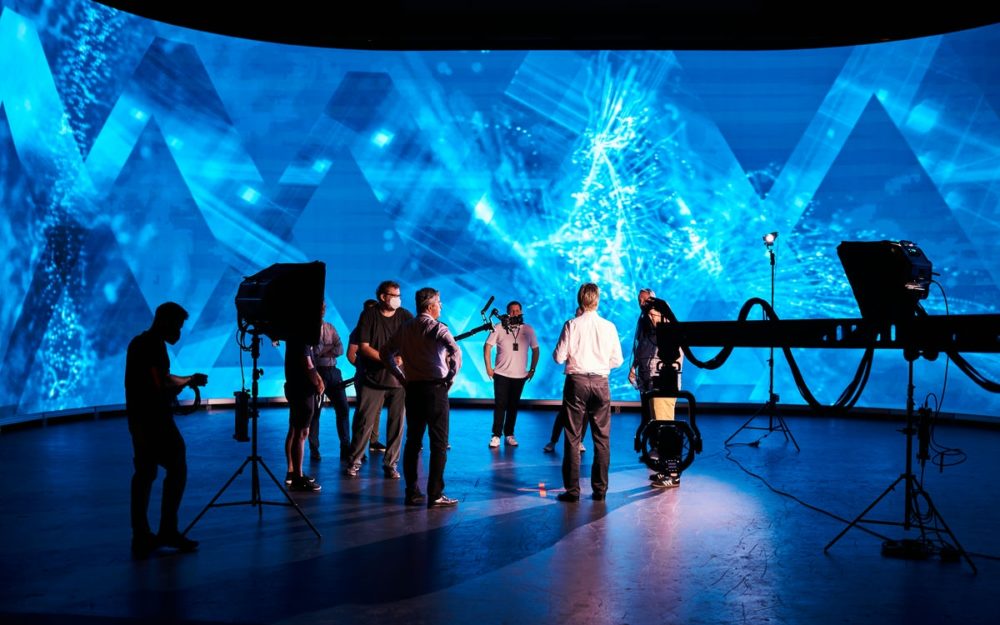 A couple of crew members and the management team of the Halostage standing in front of the LED wall.