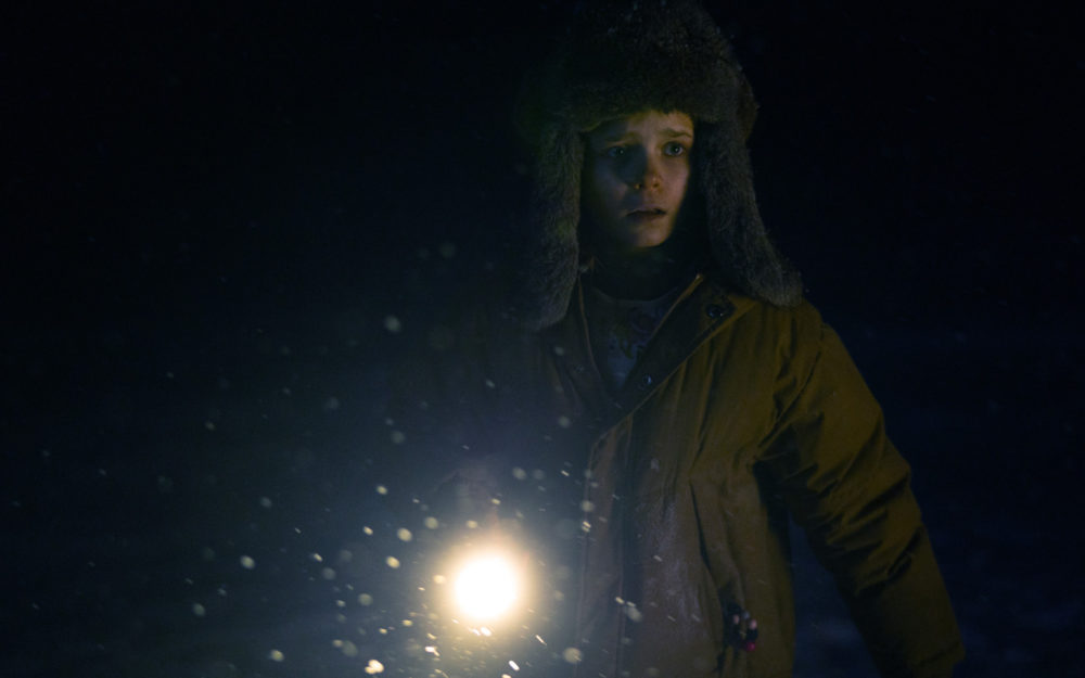 Davina Coleman walking with a torch in the dark in the Apple TV+ Series Constellation with virtual production supervision by Adrian Weber.